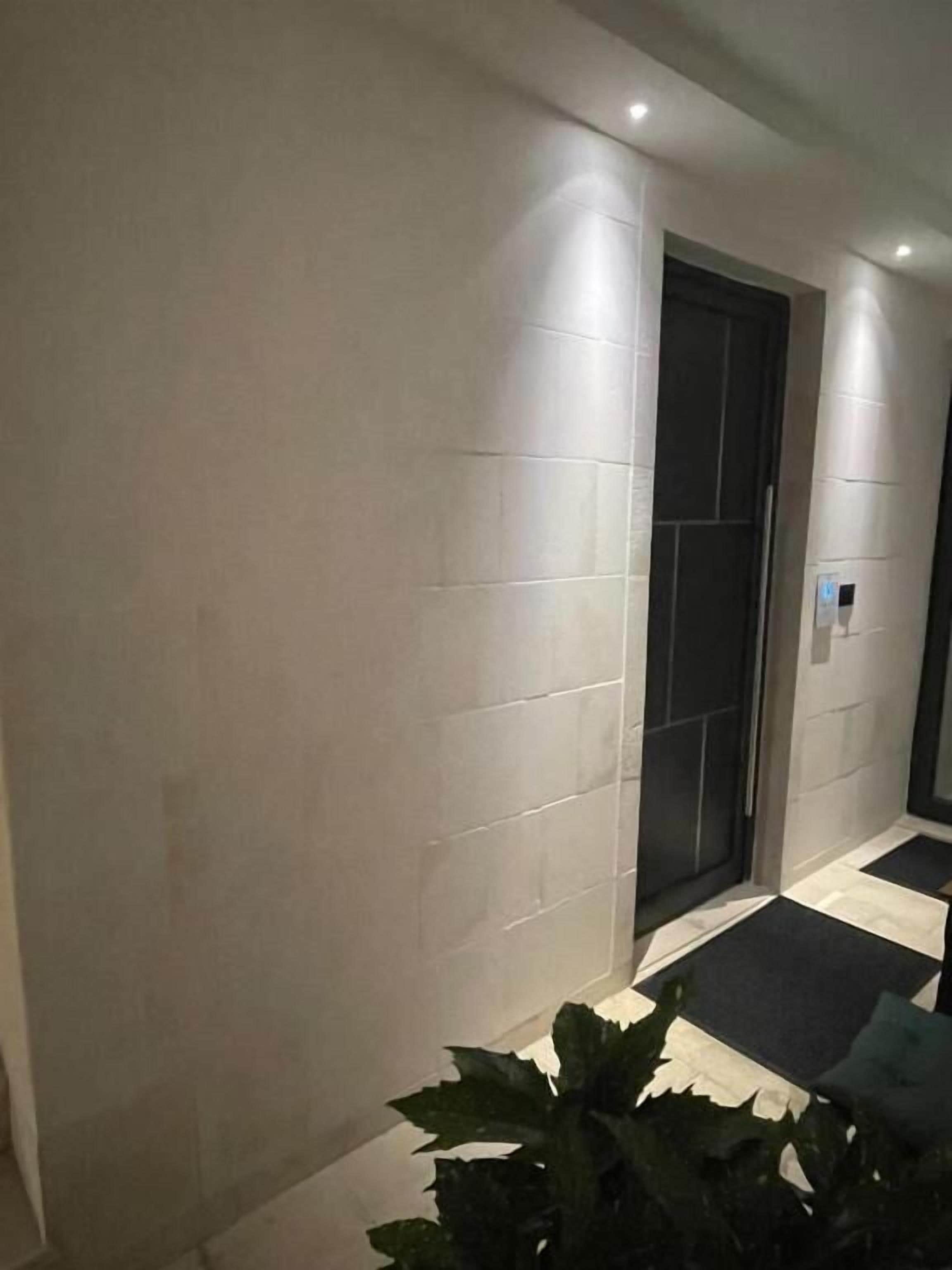 A hallway with tiled walls, a door, and a potted plant.