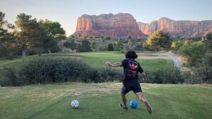 Iemand speelt voetbal op een grasveld met een berg op de achtergrond.