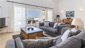 Una sala de estar moderna con un conjunto de sofá, una mesa de centro y un televisor. Hay un balcón con vista al cielo.