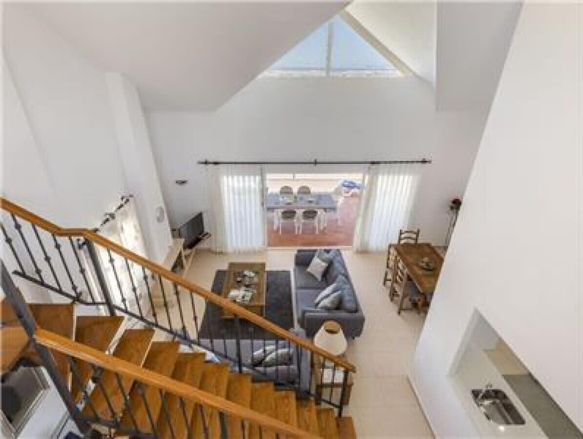 A spacious living area with a staircase, a sofa set, and a dining area.