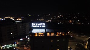 SKY HOTEL con un salón y bar visibles, rodeado de luces de la ciudad.