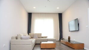 Una sala moderna con un sofá modular, una mesa de centro de vidrio y un aparador de madera.
