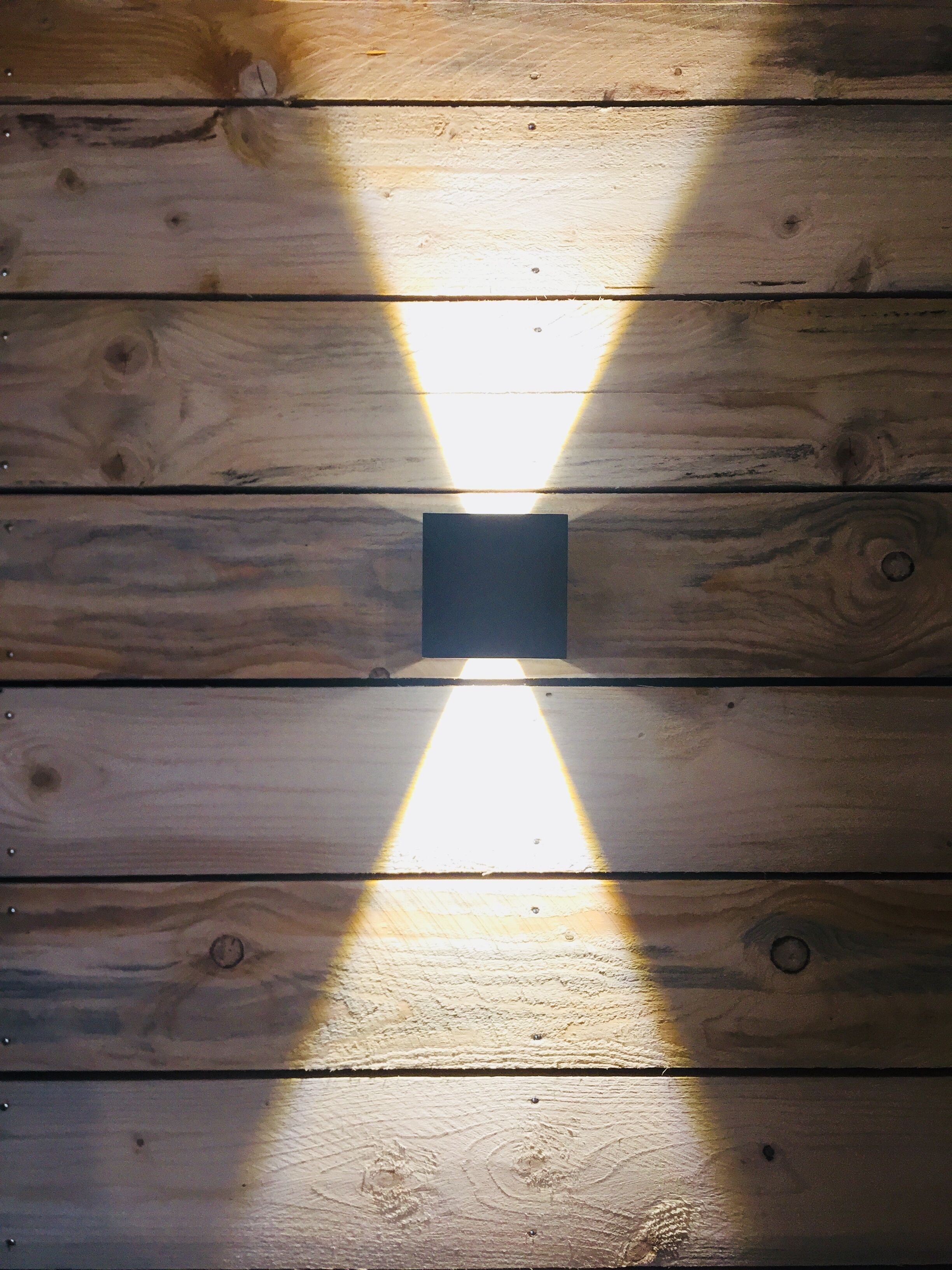 A wooden ceiling with a central light fixture casting a beam of light downwards.