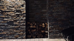 A stone wall with a fireplace and a stack of firewood.