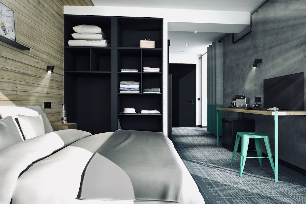 Un dormitorio moderno con cama, armario empotrado, escritorio con silla y televisor.