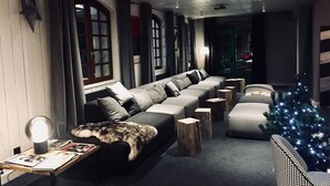 A modern living room with a sectional sofa, a small table with a lamp, and a Christmas tree.
