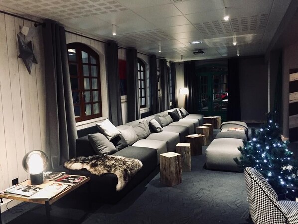 Un salon moderne avec un canapé d’angle, une petite table avec une lampe et un sapin de Noël.