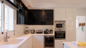 Een moderne keuken met een inbouwoven, magnetron en koffiezetapparaat.