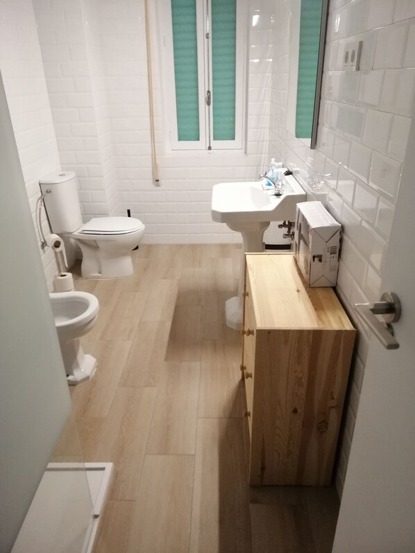 Un baño pequeño con inodoro, lavamanos y tocador de madera.