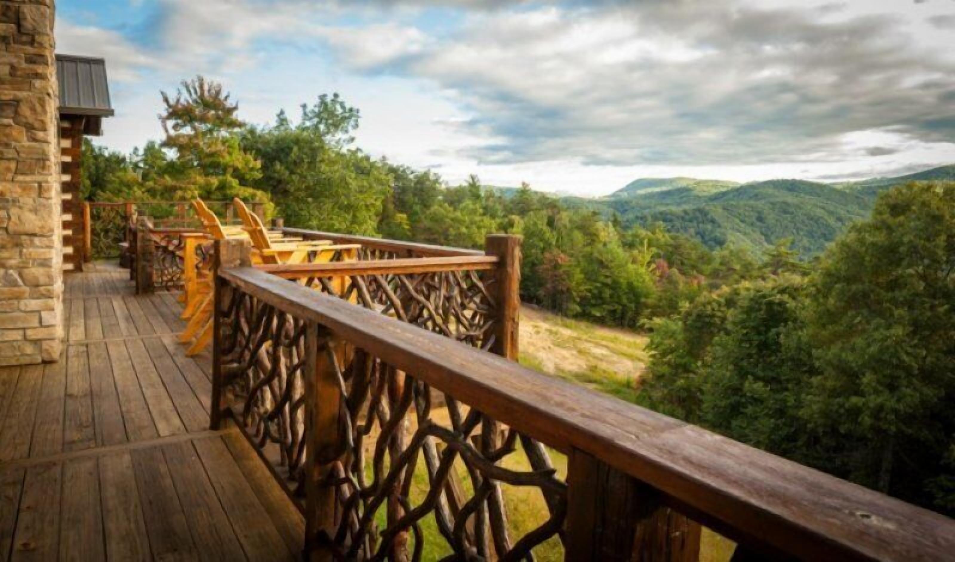 Une terrasse en bois avec une balustrade donnant sur une vallée boisée.