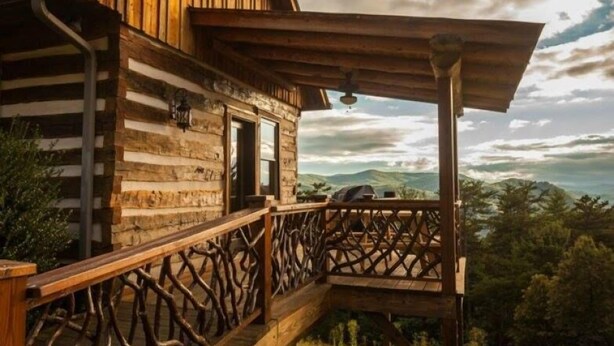 Uma cabana de madeira rústica com varanda e vista para as montanhas.