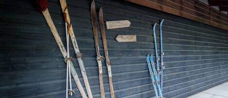 Skier und Skistöcke hängen an einer Wand, mit Hinweisschildern.