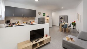 Une cuisine moderne avec des meubles de couleur sombre, un îlot central et un coin repas comprenant une table et des chaises.