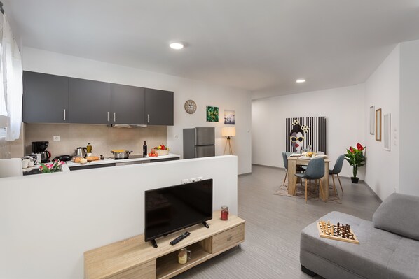 Una cocina moderna con armarios oscuros, una isla central y un comedor con mesa y sillas.