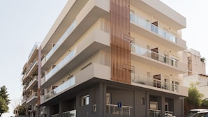 Un immeuble à plusieurs étages, doté d’une architecture moderne, avec des balcons et un panneau vertical en bois au centre de la façade.