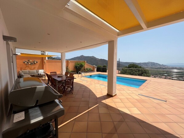 A covered outdoor area with a barbecue, a pool, and a view of the mountains. - Property with modern equipment, sea views,air conditioning, fibre optic internet (Roses)