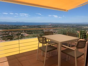 A balcony with a table and chairs, offering a view of a coastal landscape with buildings and a road. - Property with modern equipment, sea views,air conditioning, fibre optic internet (Roses)