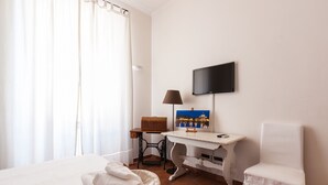 A hotel room with a bed, a desk with a lamp, a chair, and a television mounted on the wall. - Bright room near the Vatican (Roma)