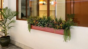 A window with a planter box containing various plants and flowers. - Hotel Saluja (Siliguri)