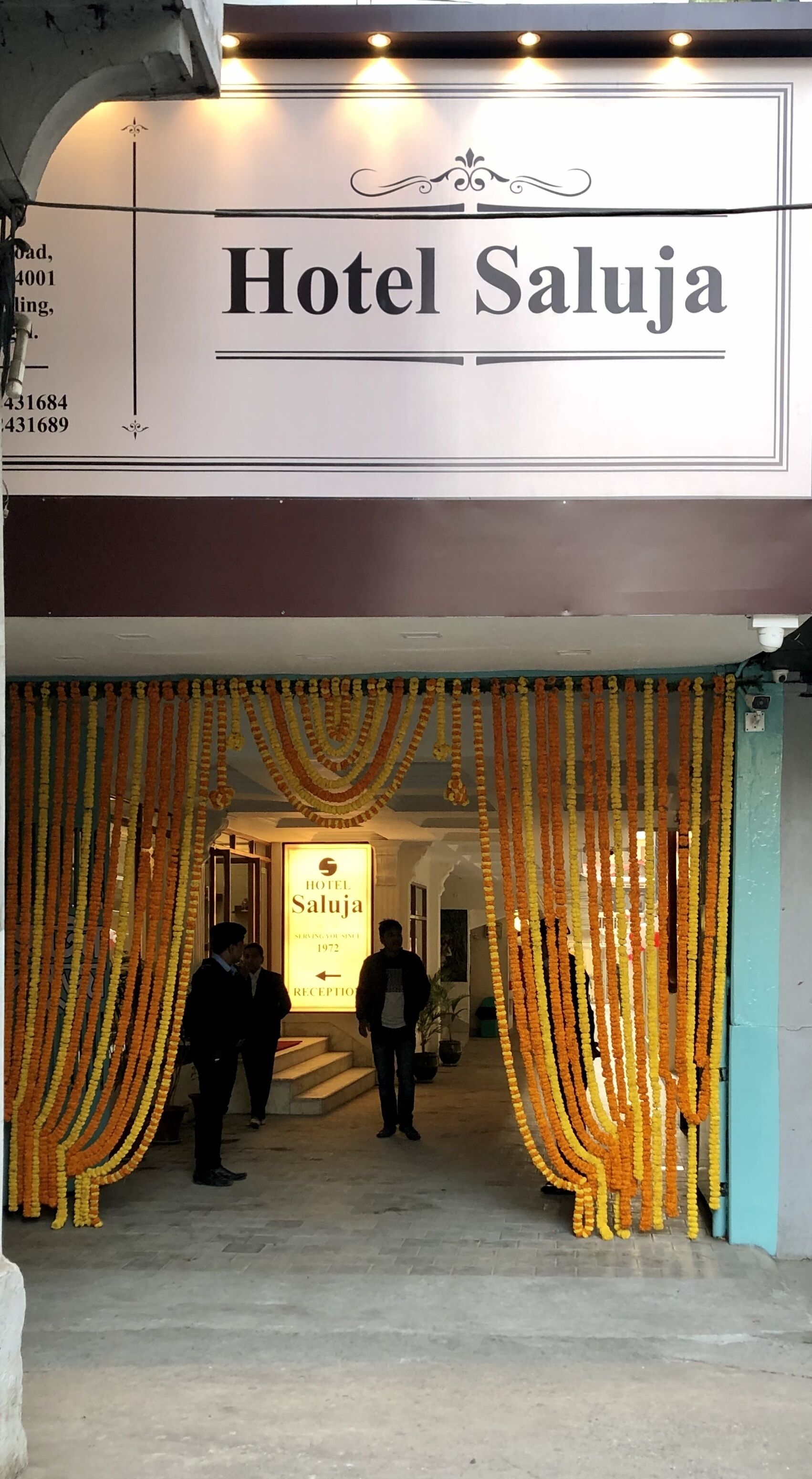 The entrance of Hotel Sahuja with a signboard and decorative garlands.
