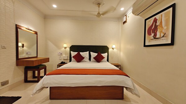 Una habitación de hotel con cama, mesitas de noche, un espejo, lámparas de pared y un cuadro enmarcado.