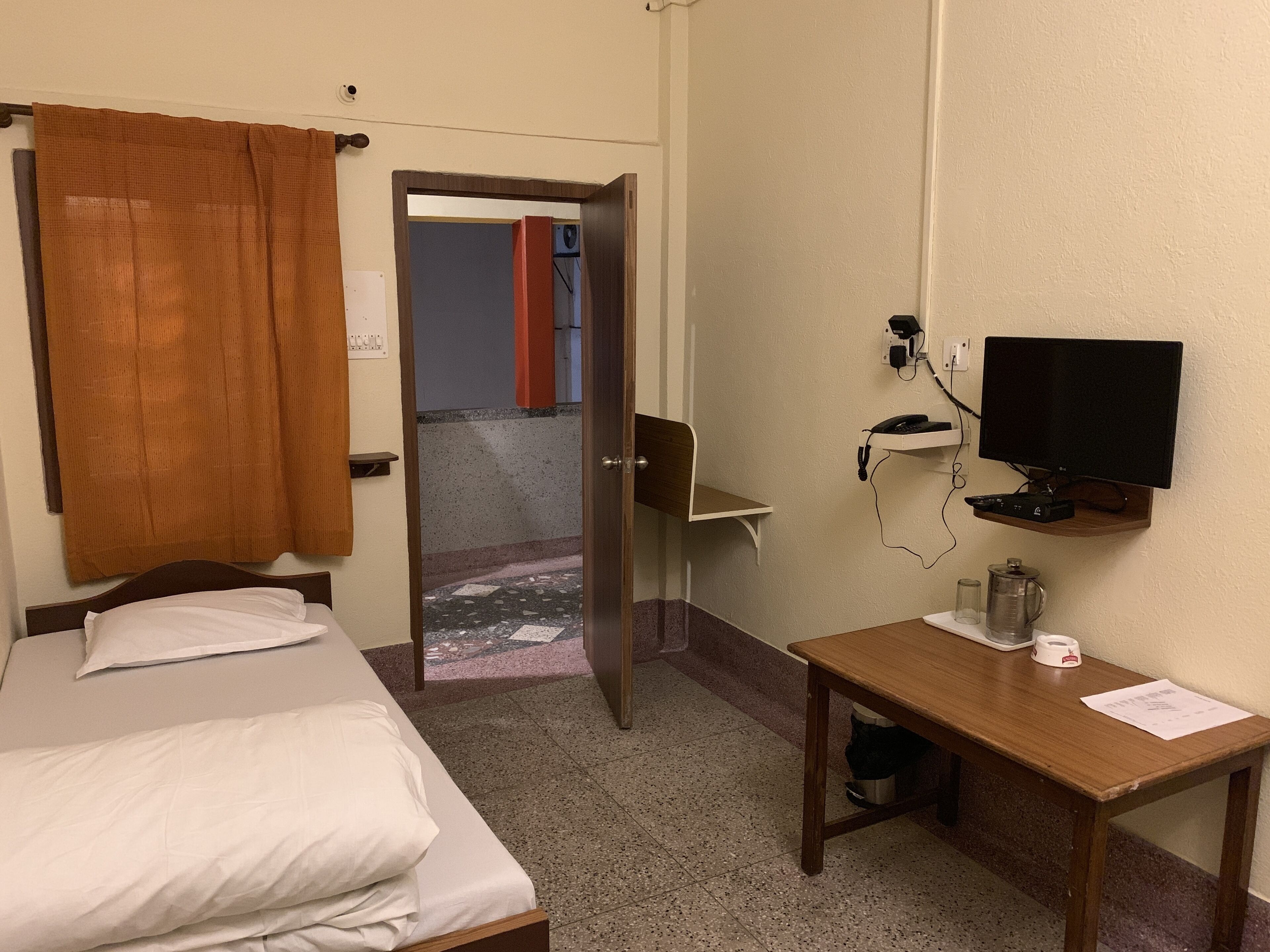 A hotel room with a bed, a desk with a computer, a television, and a coffee maker.