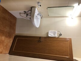 Un baño con una bañera de madera, un lavamanos blanco y un perchero para toallas.