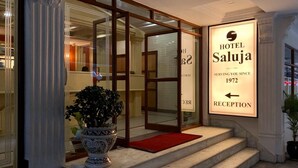 A hotel entrance with a reception sign, a potted plant, and a staircase leading to the entrance. - Hotel Saluja (Siliguri)