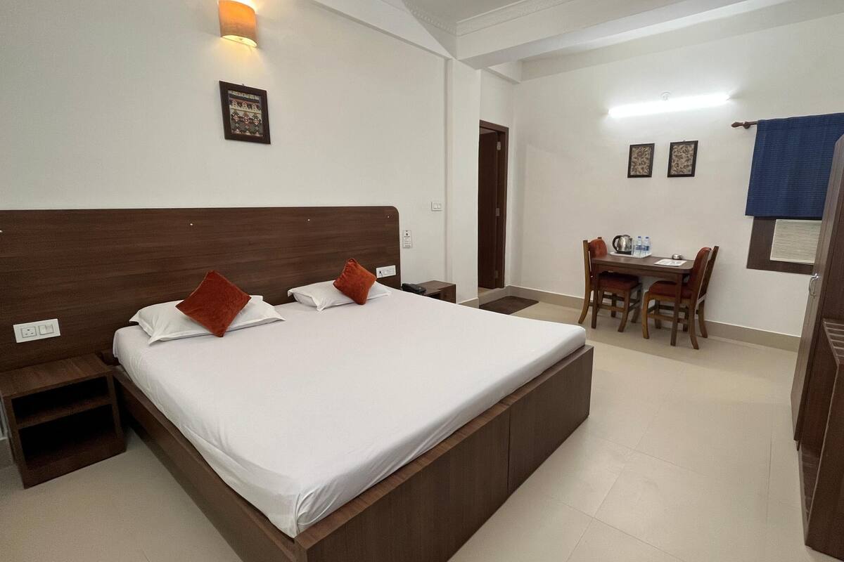 A hotel room with a large bed, a desk, and a chair.