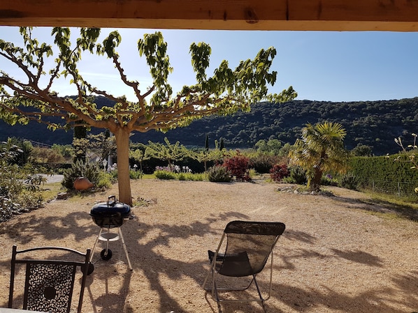 Un espacio al aire libre techado con una parrilla, una silla plegable y una mesa.