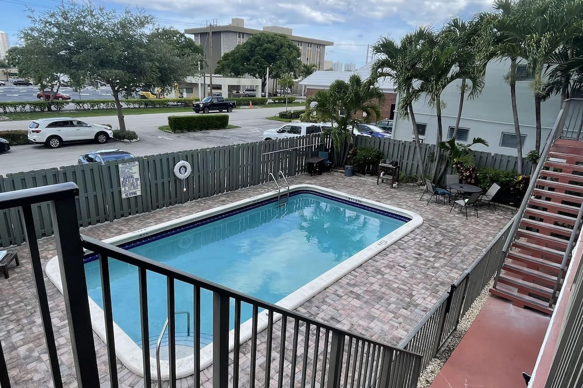 A rectangular pool with a metal railing, surrounded by a brick patio.