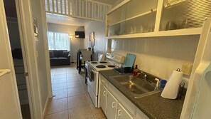 Cozinha compacta com fogão, pia e bancada.
