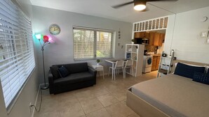 A compact living space with a kitchenette, a dining area, and a bed. - Petrina Studio Apartment (Pompano Beach)