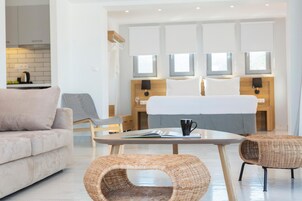 Una habitación de hotel moderna con un sofá, una mesa de comedor y dos sillas de mimbre.