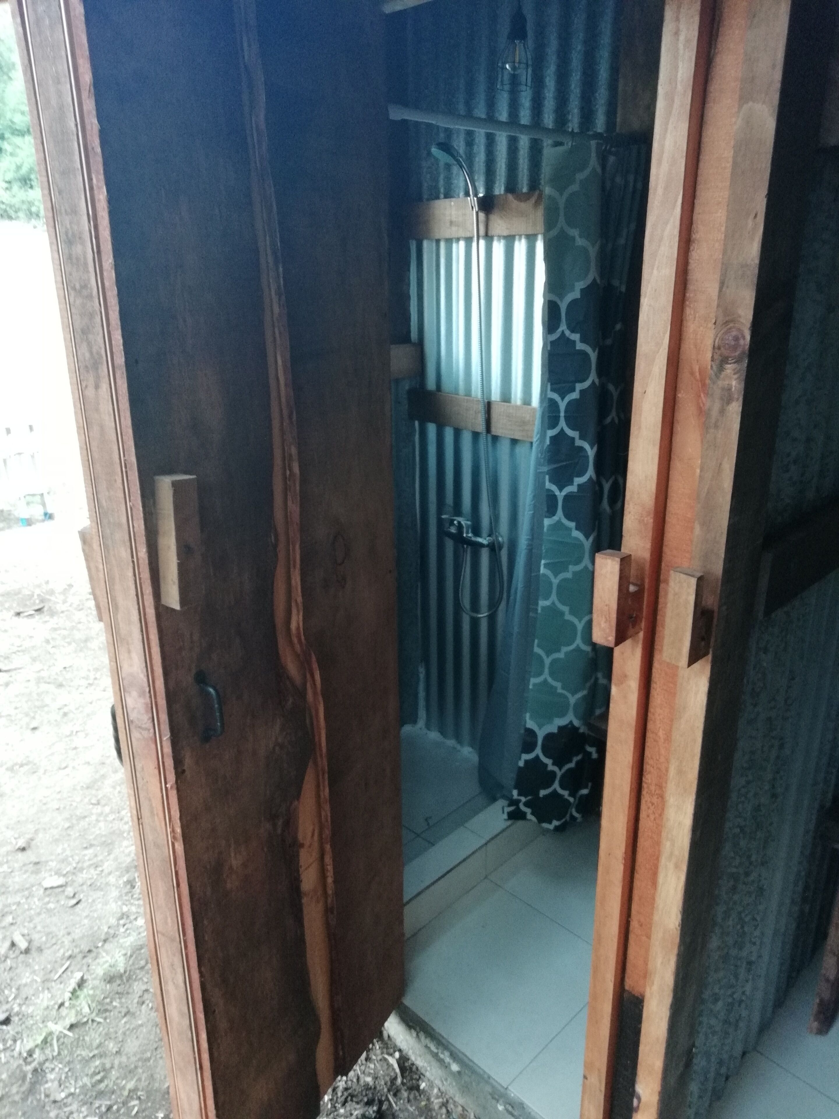 A wooden door leading to a bathroom with a shower area.