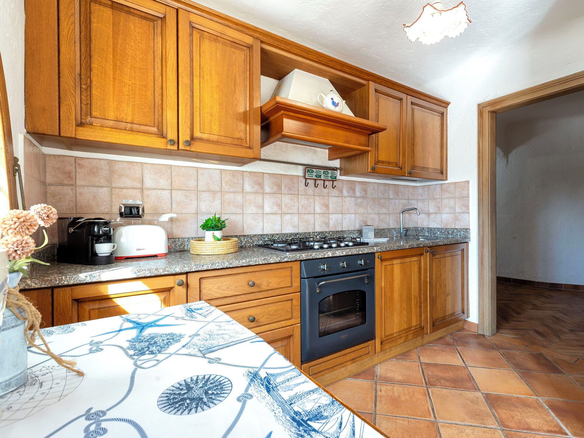 Una cocina con armarios de madera, una estufa a gas, un horno, un fregadero y una encimera con un tostador y una planta.