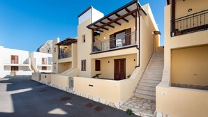 A residential building with multiple balconies, a stone staircase, and a clear sky. - I Tre Golfi Ghaliya Apartment (San Vito Lo Capo)