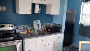 A compact kitchen with white cabinets, a stainless steel stove, and a refrigerator.