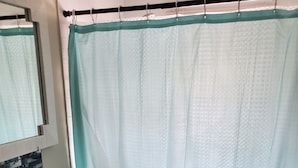 A bathroom with a sink, mirror, and a shower curtain.