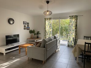A modern living room with a sofa, TV, and a dining area with a table and chairs. - Les Villas de Castel : Villa "Les Muriers (Castelmaurou)