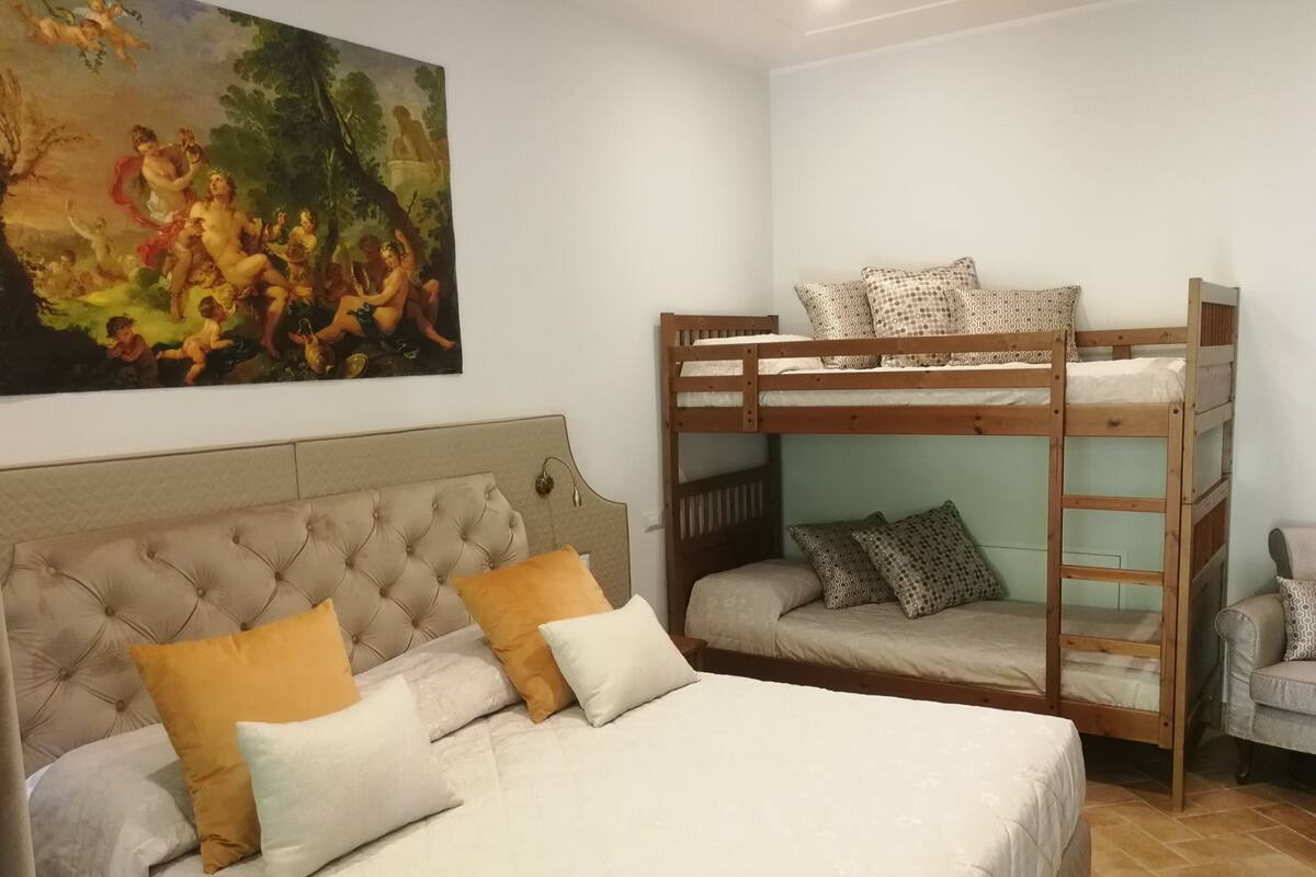 Quarto com uma cama grande, uma cama beliche e um quadro na parede.