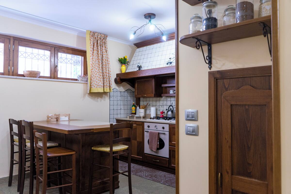 Cozinha com armários de madeira, fogão e janela com cortina.
