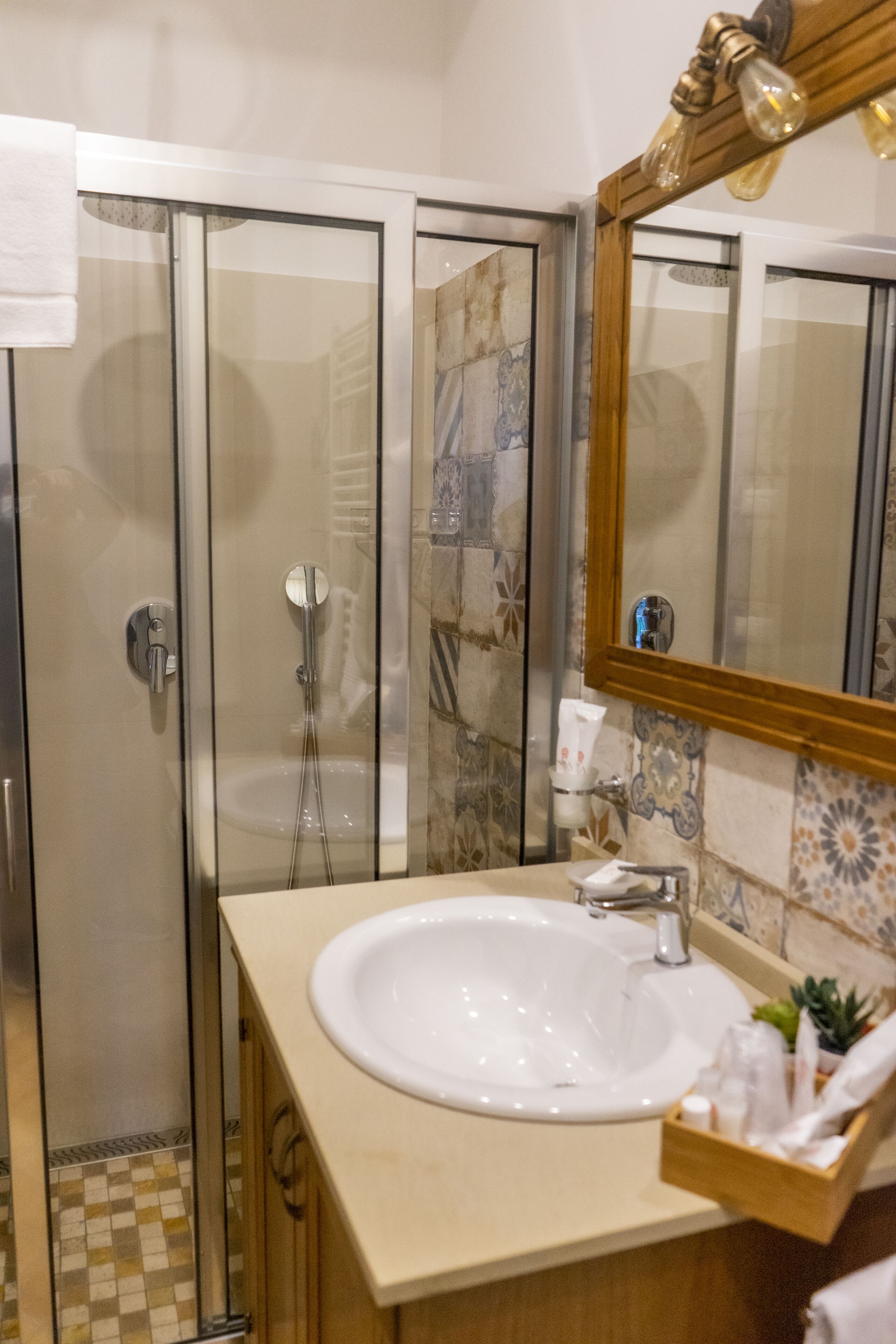 Une salle de bain avec une douche à parois de verre, un lavabo blanc et un miroir avec un cadre en bois.