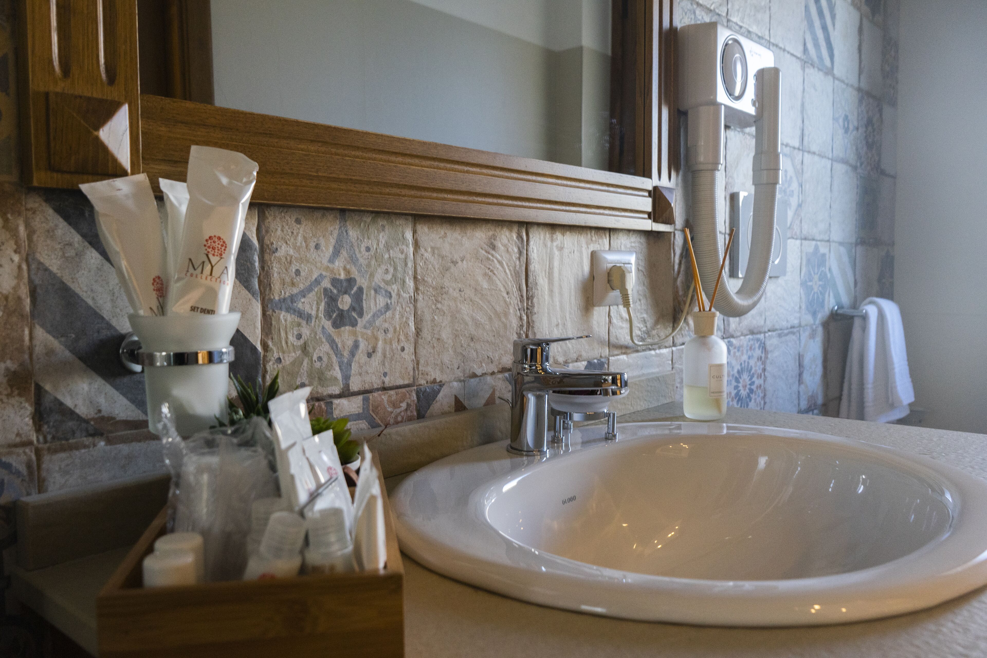 A bathroom with a white sink, a mirror above it, and a towel hanging on the wall.