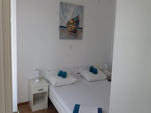 Ein Schlafzimmer mit einem Bett, zwei Nachttischen, einem Bild an der Wand und einer weißen Tür.