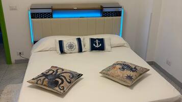 A bed with a headboard, two pillows, and a bedside table with a lamp.