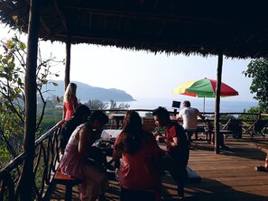 A wooden deck with outdoor seating and a view of the ocean.