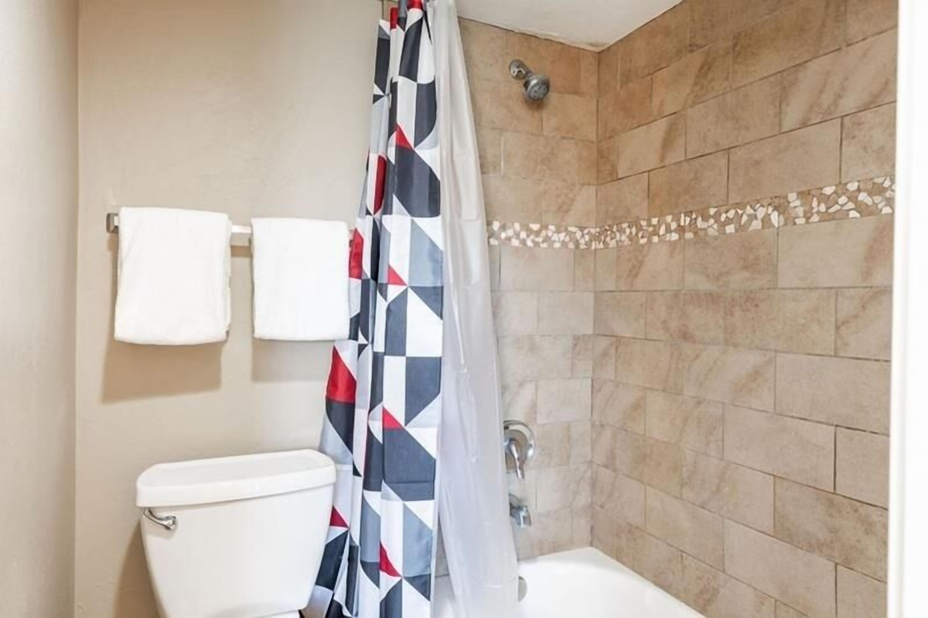 Une salle de bain comprenant des toilettes, un lavabo et un espace douche avec un rideau de douche à motifs.