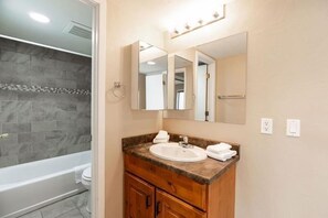 A bathroom with a bathtub, a sink with a mirror above it, and a towel rack. - Breakaway West Convenient Condo Near Vail Village by RedAwning (Vail)