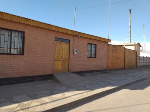 A brick building with a flat roof and large wooden doors. - Hostal Casa Colque (San Pedro de Atacama)